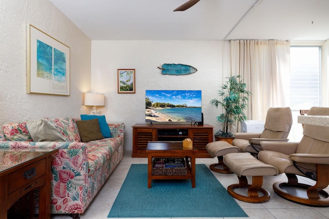 tiled living room featuring a textured wall and a ceiling fan