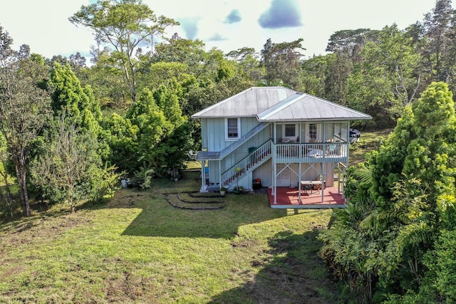 back of property with a lawn, stairway, metal roof, a deck, and board and batten siding