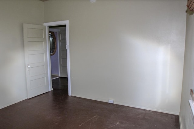 spare room with concrete flooring and baseboards