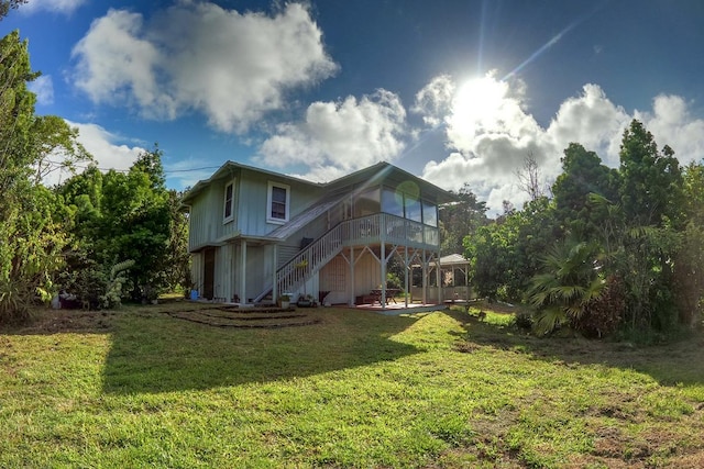 rear view of property with stairway and a lawn
