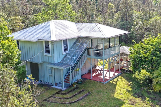 back of property with a sunroom, stairs, a wooden deck, a lawn, and board and batten siding