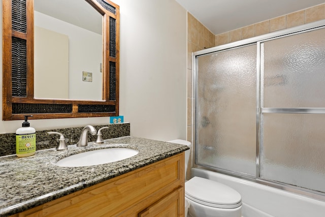 bathroom featuring bath / shower combo with glass door, toilet, and vanity
