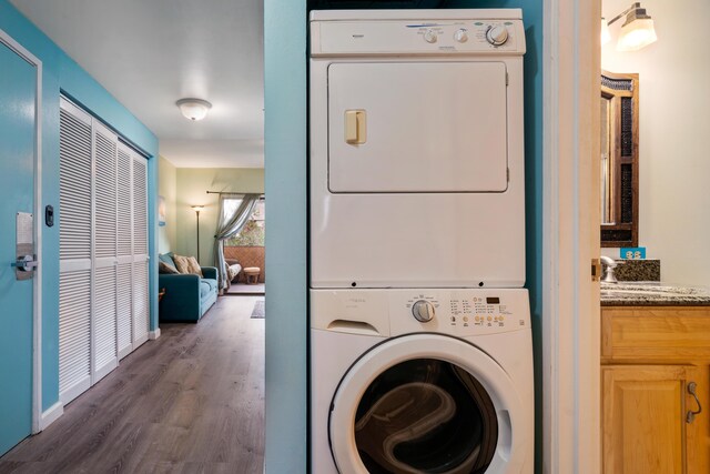 laundry area with stacked washer and clothes dryer and dark wood-style flooring