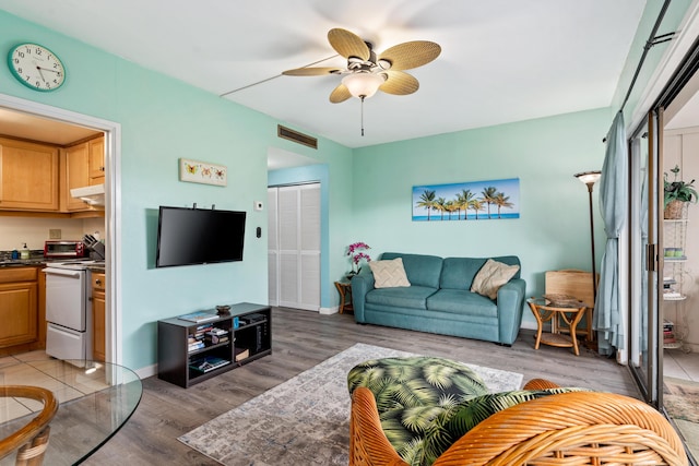 living room featuring light wood-style flooring, ceiling fan, and baseboards