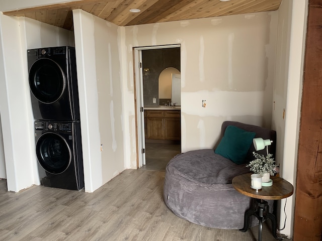 living area featuring stacked washing maching and dryer, wooden ceiling, and light wood finished floors