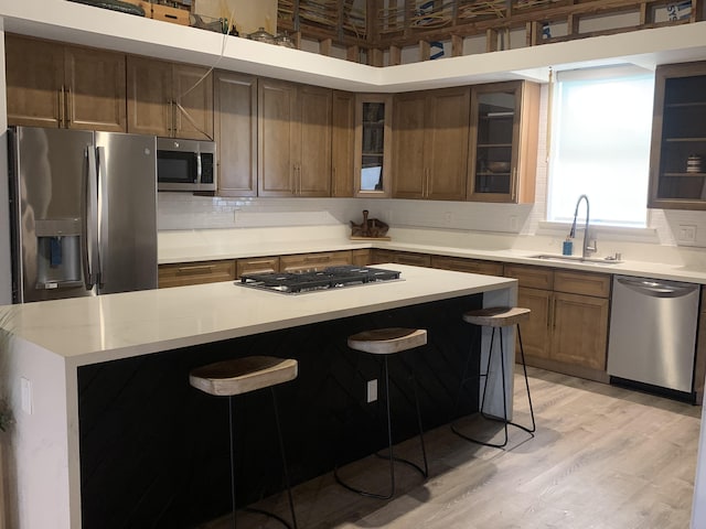 kitchen featuring stainless steel appliances, decorative backsplash, a sink, and a kitchen bar