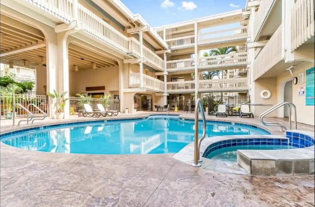 community pool featuring a hot tub, a patio, and fence