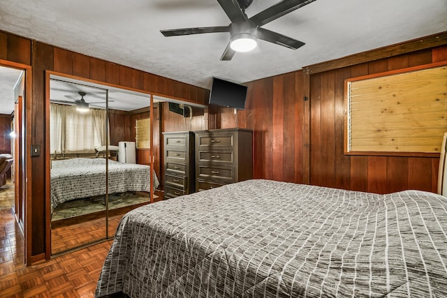 bedroom with ceiling fan and wooden walls