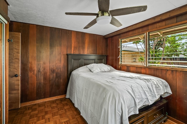 bedroom with a ceiling fan and wood walls