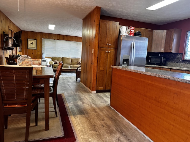 73-1228 Kaiminani Dr, Kailua-Kona, HI 96740 - kitchen with stainless steel refrigerator with ice dispenser, black microwave, light wood-type flooring, wood walls, and a textured ceiling