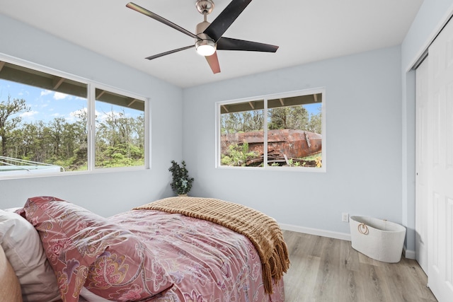 bedroom with a closet, wood finished floors, baseboards, and ceiling fan