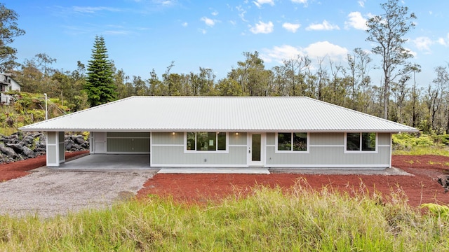 single story home featuring driveway, metal roof, and a carport
