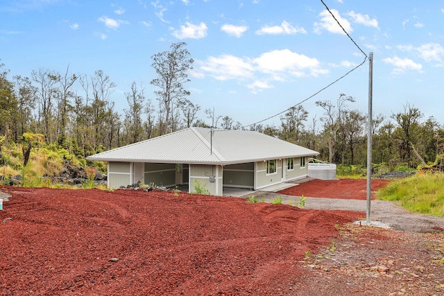 ranch-style home with dirt driveway and metal roof