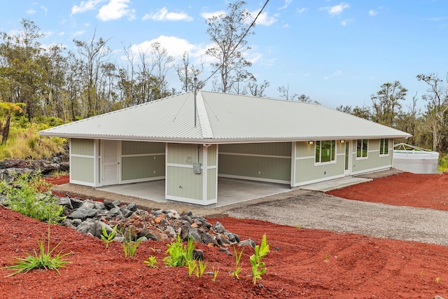 rear view of house with metal roof and driveway