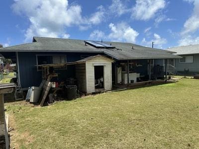 back of property featuring a yard, solar panels, and a sunroom