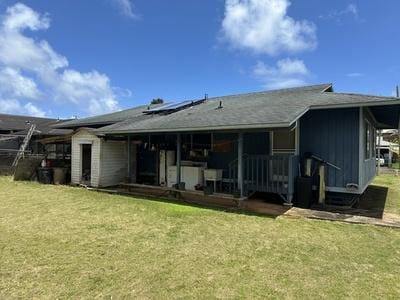 rear view of house with a lawn and solar panels