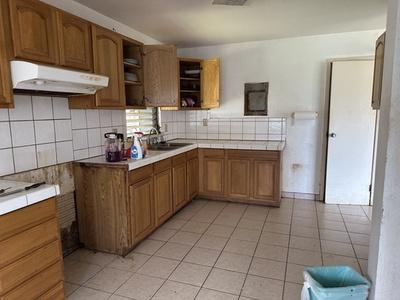 kitchen featuring light tile patterned floors, open shelves, under cabinet range hood, and backsplash