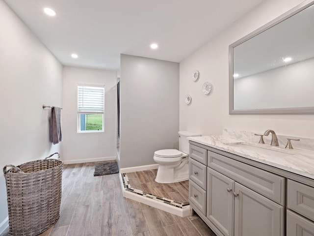 bathroom with walk in shower, wood finished floors, vanity, toilet, and recessed lighting