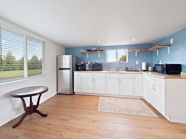 kitchen with freestanding refrigerator, white cabinetry, open shelves, and black microwave