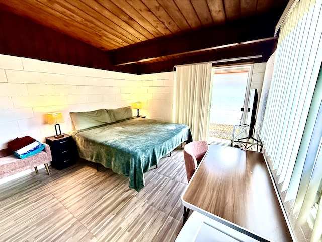 bedroom with wood ceiling, wood finished floors, concrete block wall, and access to exterior