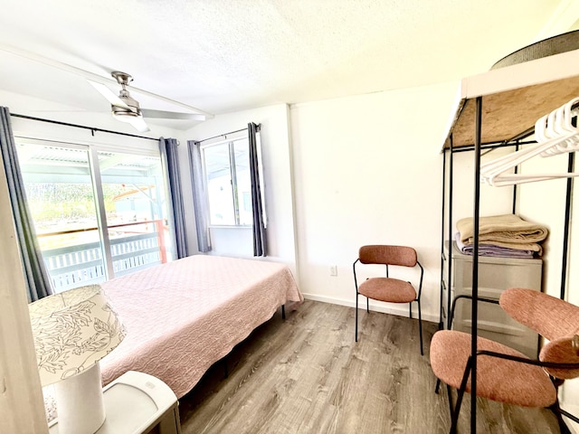bedroom with baseboards, access to outside, a textured ceiling, and wood finished floors