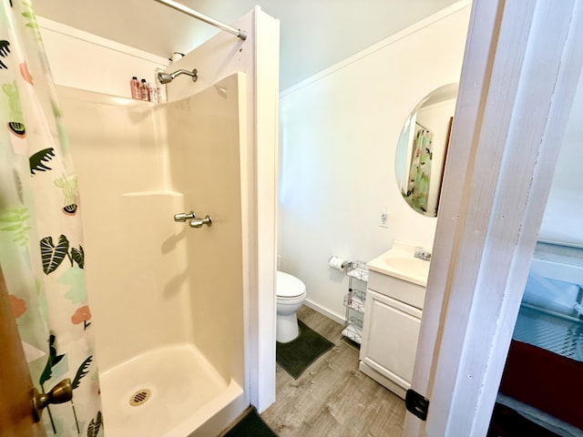bathroom featuring vanity, toilet, a shower stall, and wood finished floors