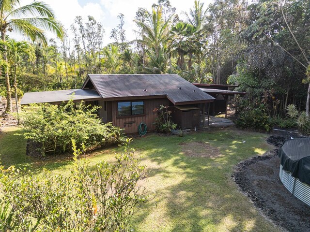 rear view of house featuring metal roof, board and batten siding, and a lawn