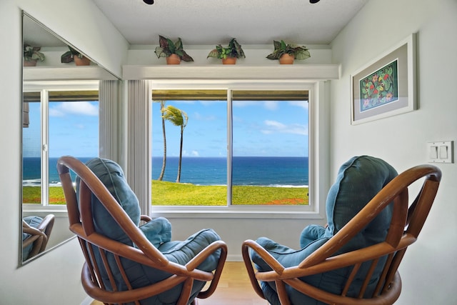 living area with a wealth of natural light, a water view, and wood finished floors