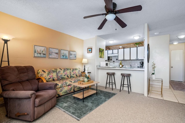 living room featuring carpet, ceiling fan, and a textured ceiling