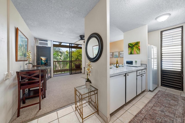 kitchen featuring white appliances, a textured ceiling, light tile patterned floors, a ceiling fan, and a wall unit AC