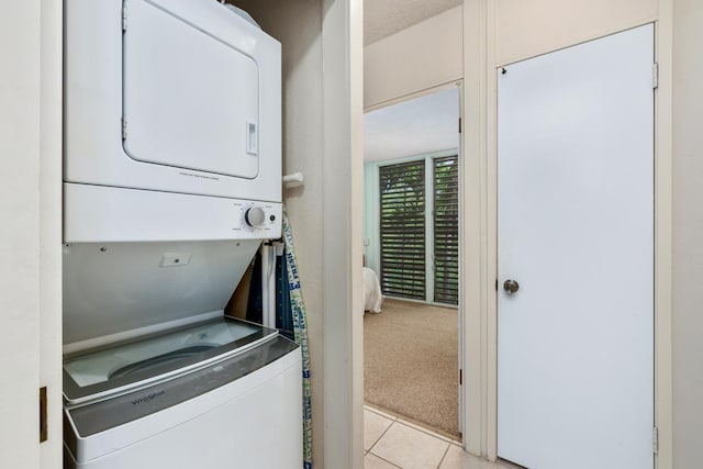 laundry area with stacked washing machine and dryer, light colored carpet, and light tile patterned floors