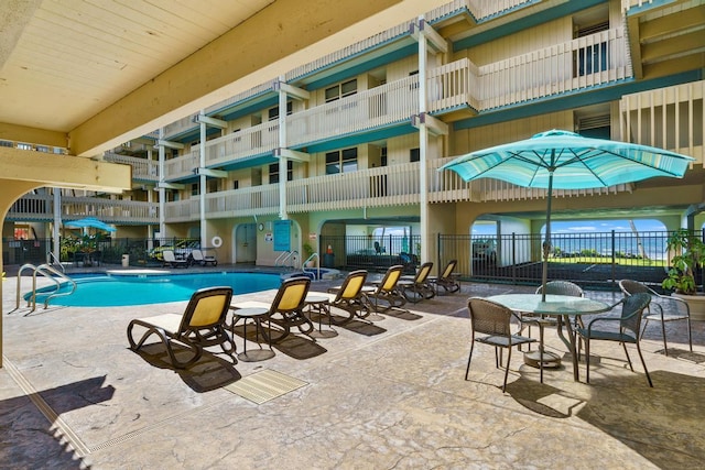 community pool with fence and a patio area