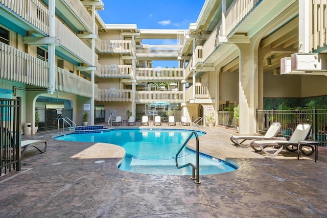 community pool with a patio and fence
