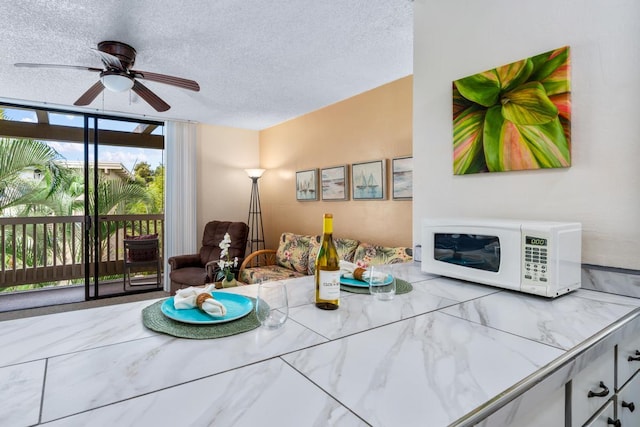living area featuring a ceiling fan, floor to ceiling windows, and a textured ceiling
