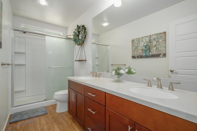 bathroom with a sink, toilet, a shower stall, and wood finished floors