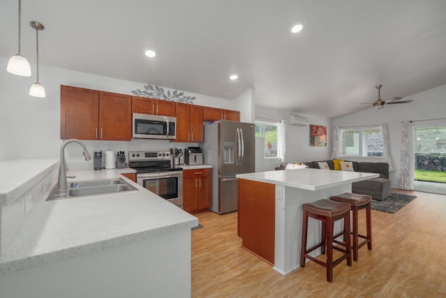 kitchen featuring light wood-type flooring, appliances with stainless steel finishes, a kitchen bar, and a sink