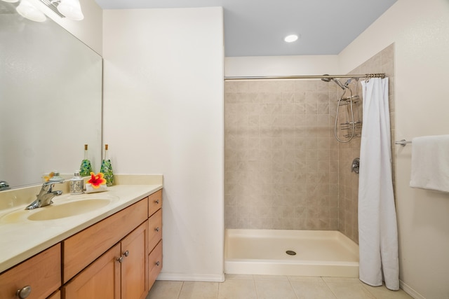 full bathroom with tile patterned floors, tiled shower, vanity, and baseboards