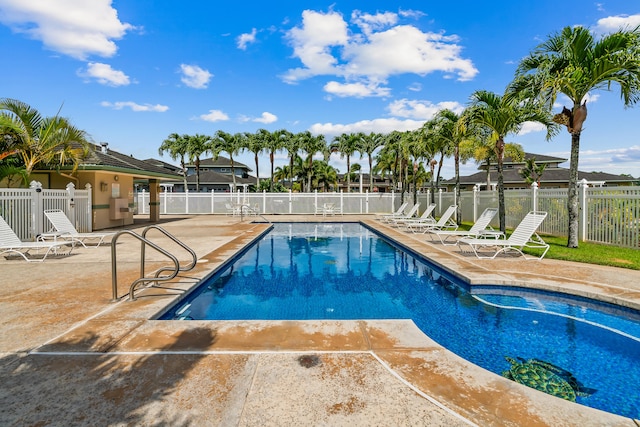community pool with a patio area and fence