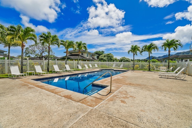 community pool with a patio area, fence, and a mountain view