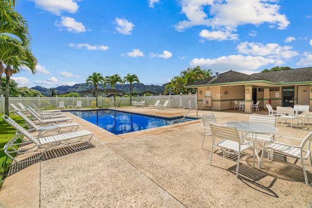 community pool with a fenced backyard, a patio area, and a mountain view