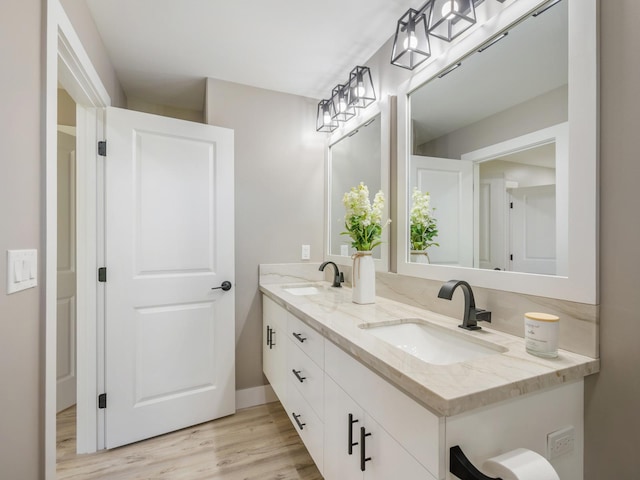 bathroom with wood finished floors, double vanity, and baseboards