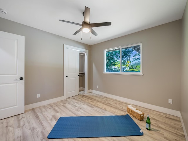 exercise area with wood finished floors, a ceiling fan, and baseboards