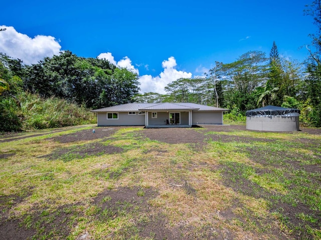 rear view of property with a yard and metal roof