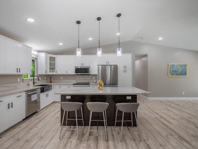 kitchen featuring appliances with stainless steel finishes, vaulted ceiling, a sink, a center island, and a breakfast bar area