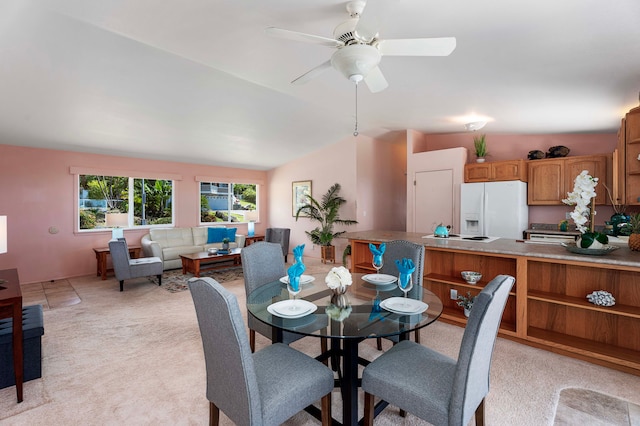 dining area featuring light carpet, lofted ceiling, and ceiling fan