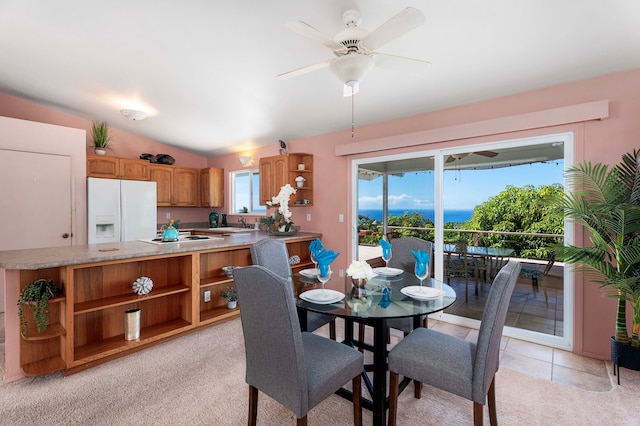 dining area with ceiling fan, light colored carpet, and lofted ceiling