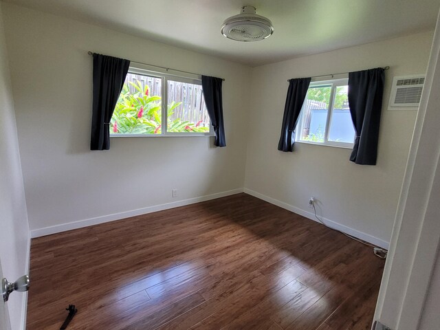spare room with wood finished floors, a wall mounted AC, and baseboards