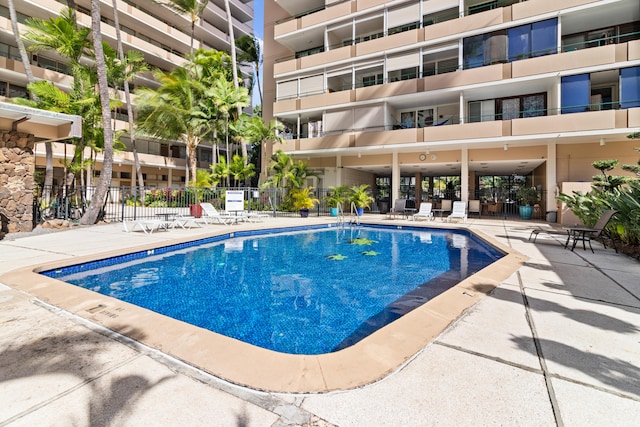community pool with fence and a patio
