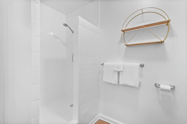 full bath featuring a tile shower and baseboards