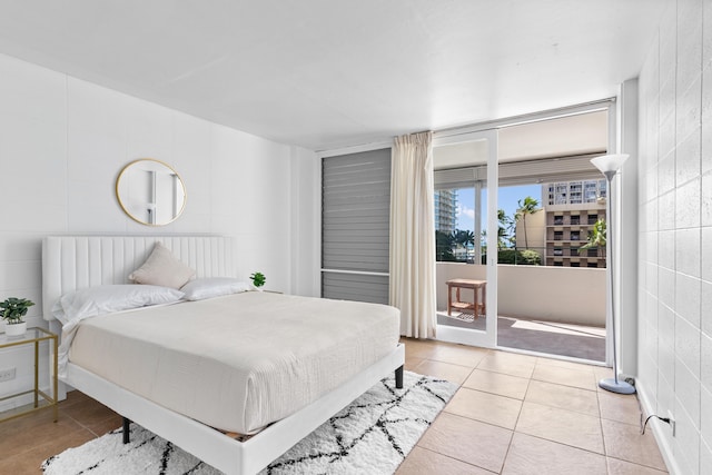 bedroom with light tile patterned floors, access to exterior, and tile walls